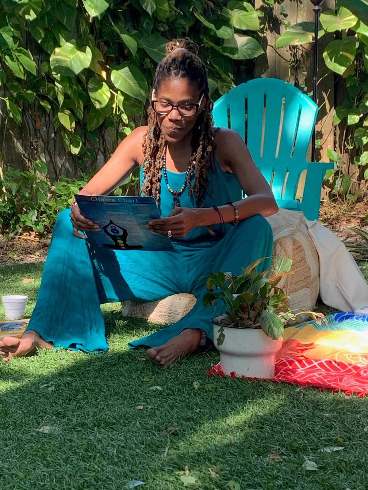 Malinda D. Ellis reading a chakra chart in a sunlit garden
